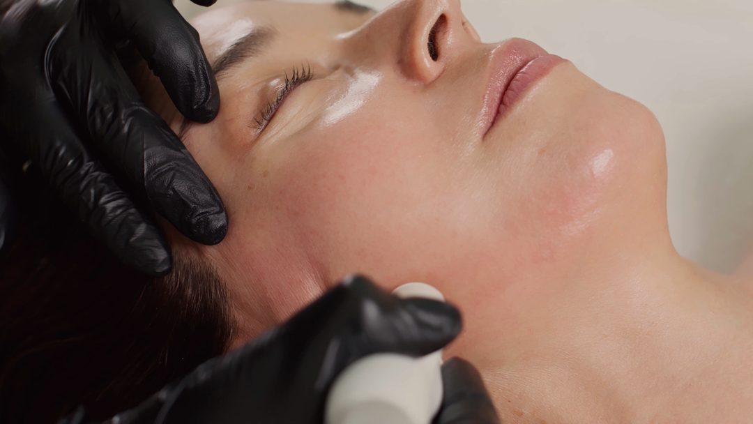 A facial device being guided along a client’s jawline