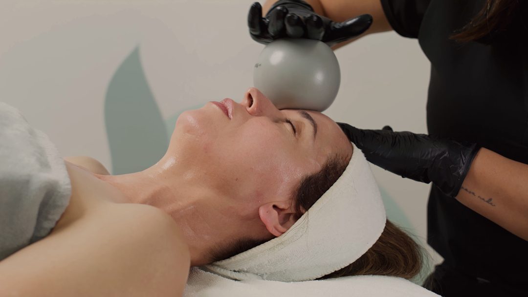 A practitioner and client during a facial treatment in a light-filled room